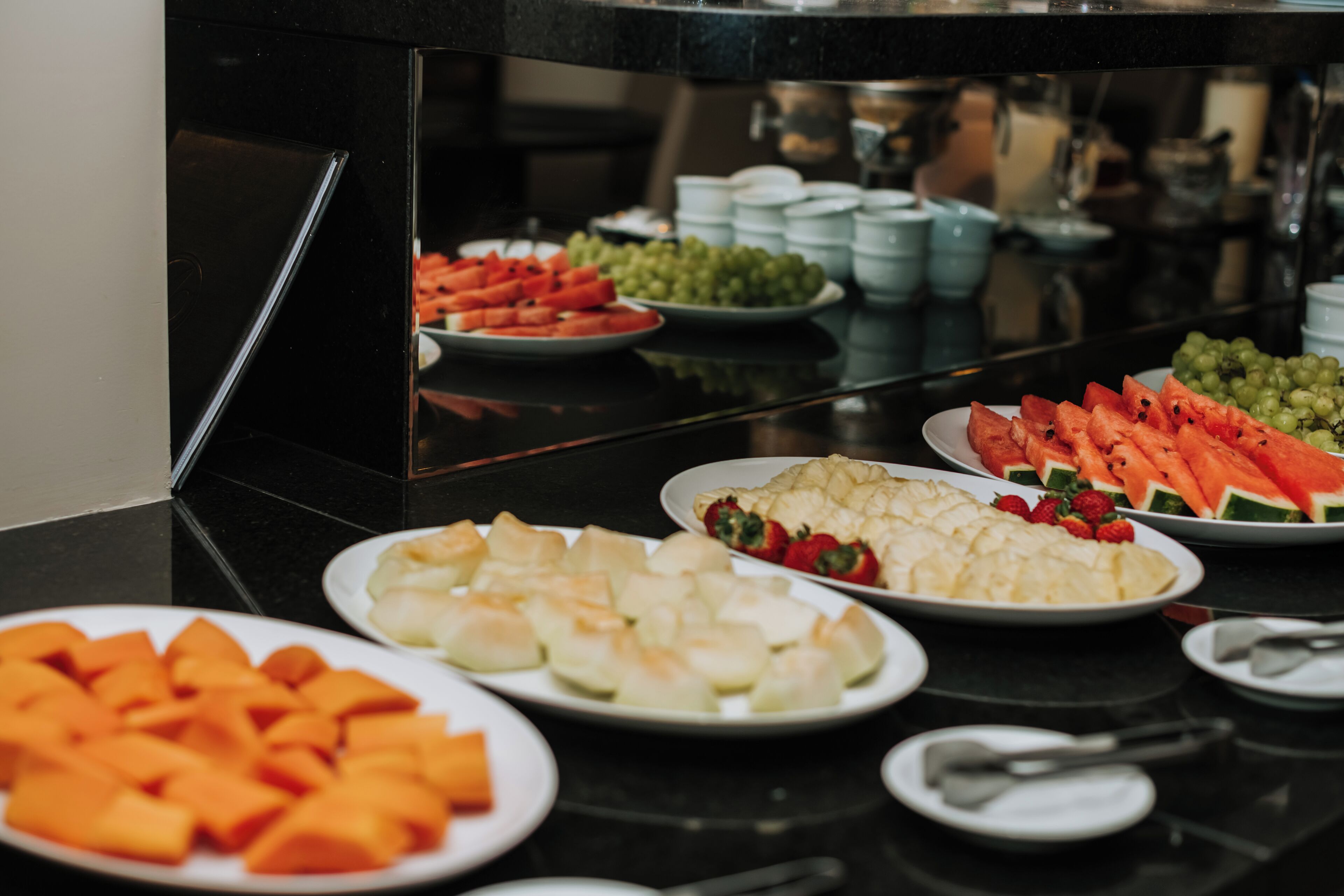 A buffet table with various food items including watermelon, grapes, and other fruits.