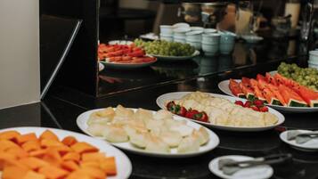 A buffet table with various food items including watermelon, grapes, and other fruits.