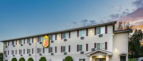 A Super 8 hotel with a parking lot, multiple windows, and a signboard.