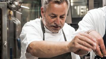 A chef in a professional kitchen with stainless steel appliances and a focus on food preparation.
