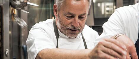 Un chef en una cocina profesional con electrodomésticos de acero inoxidable y énfasis en la preparación de alimentos.