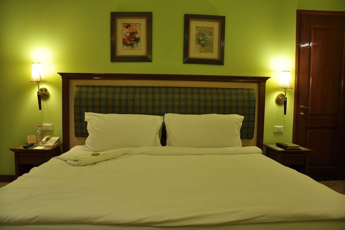 A neatly made bed with a headboard, two bedside lamps, and a framed picture above the bed.