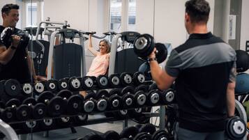 A gym with weightlifting equipment and dumbbells.