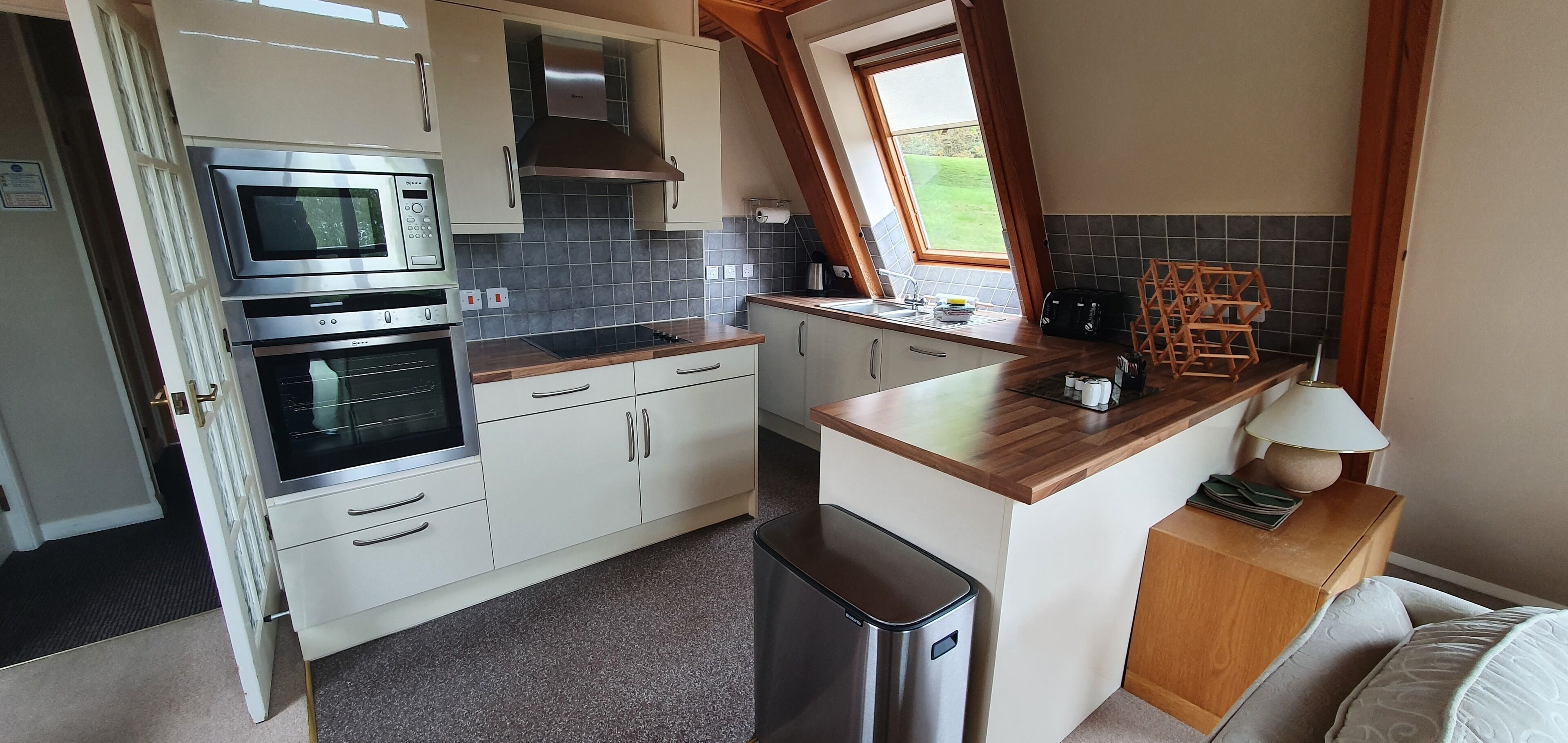 A compact kitchen with built-in appliances, a window, and a small island with a lamp.