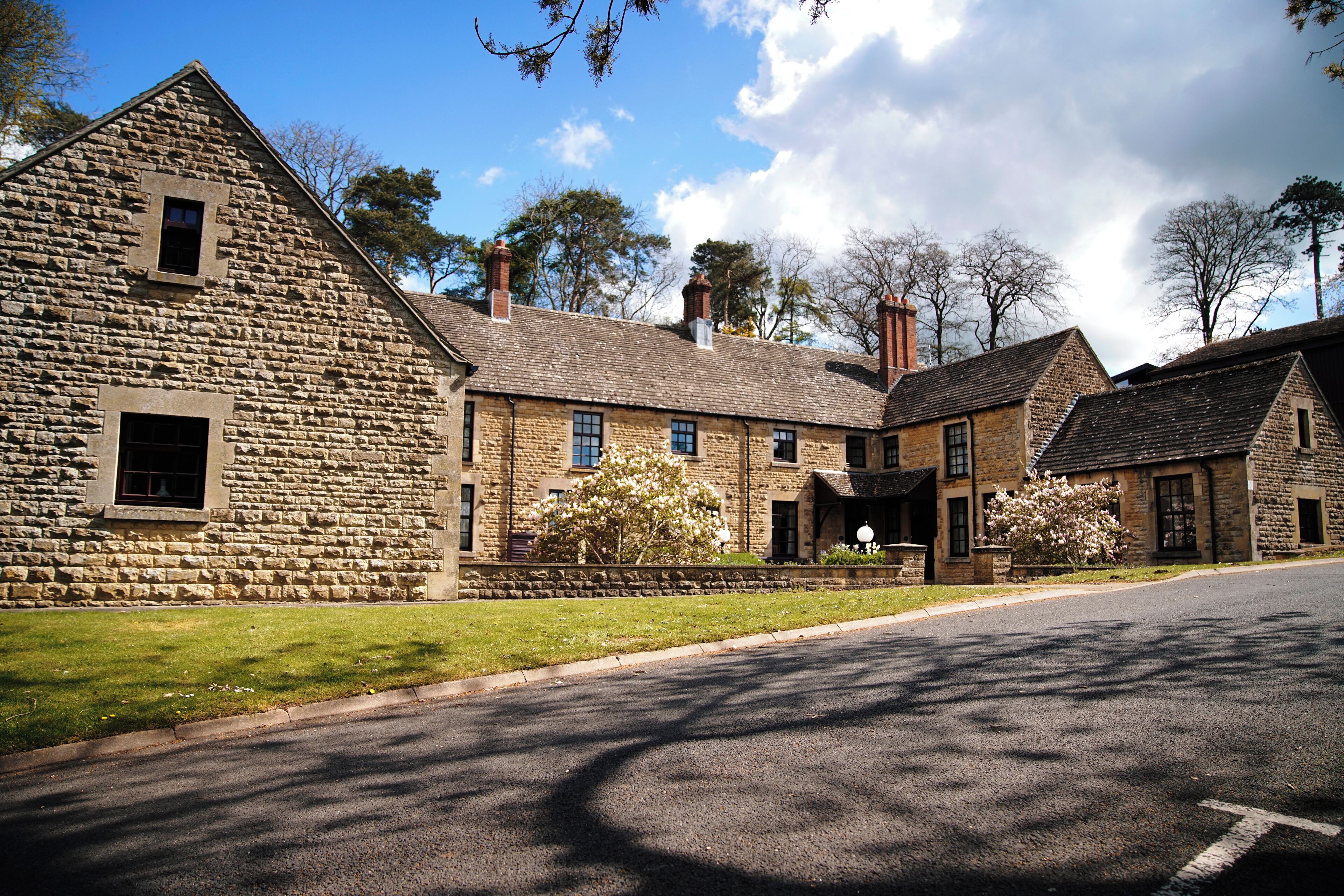 A stone building with multiple windows and a lawn in front.