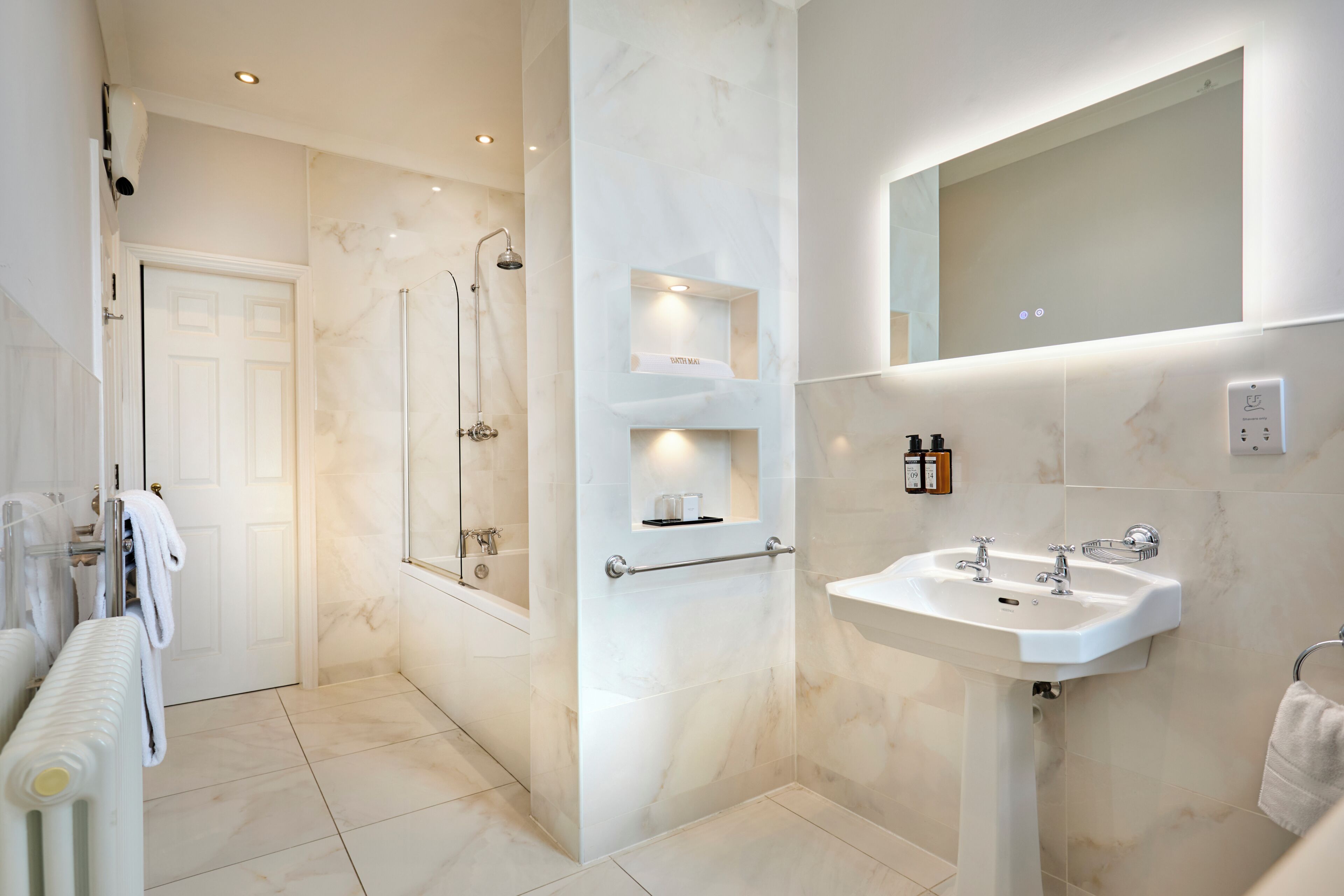 A modern bathroom with a bathtub, a sink, and a mirror.