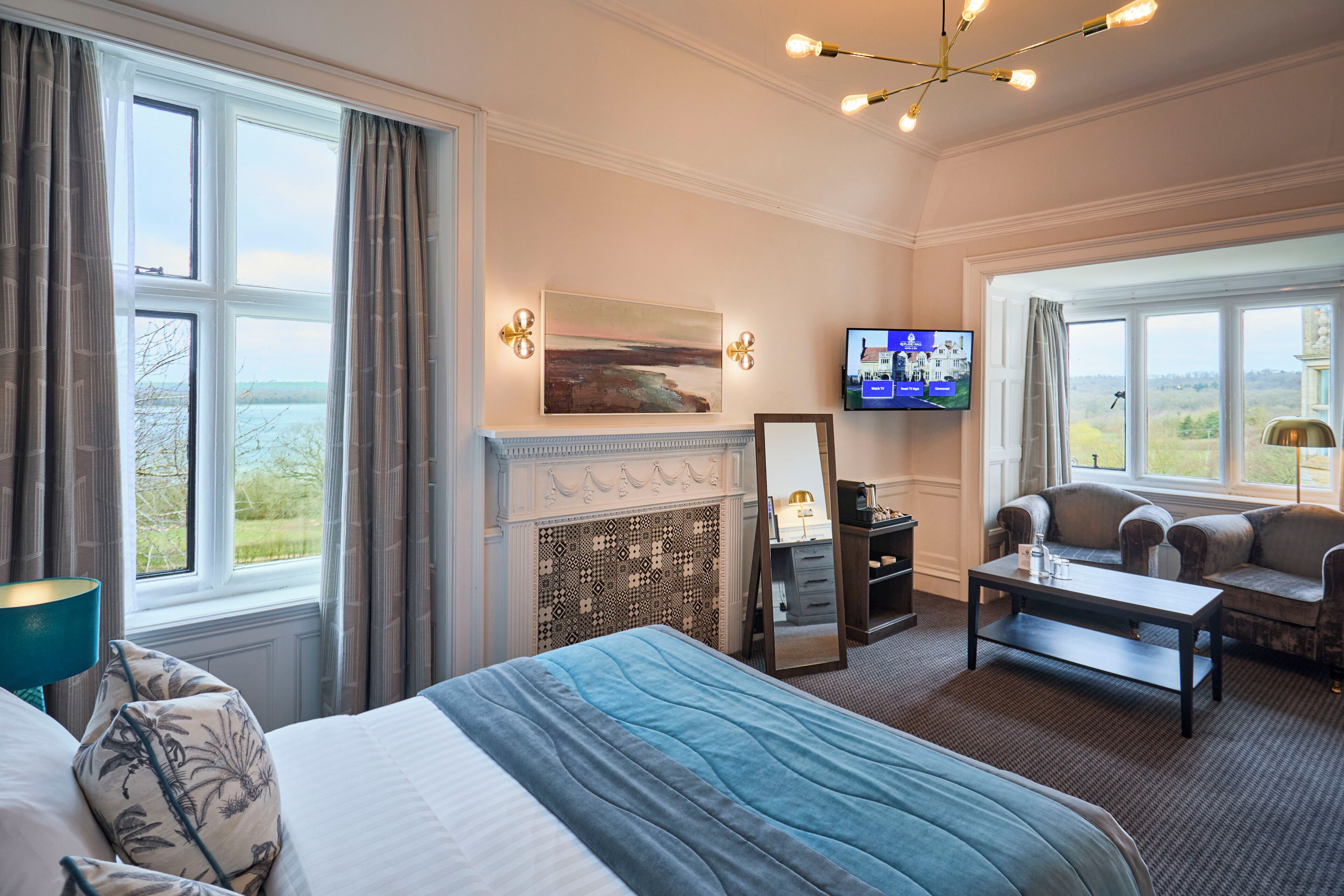 A hotel room with a bed, a fireplace, a television, a sofa, and a view of the outdoors.