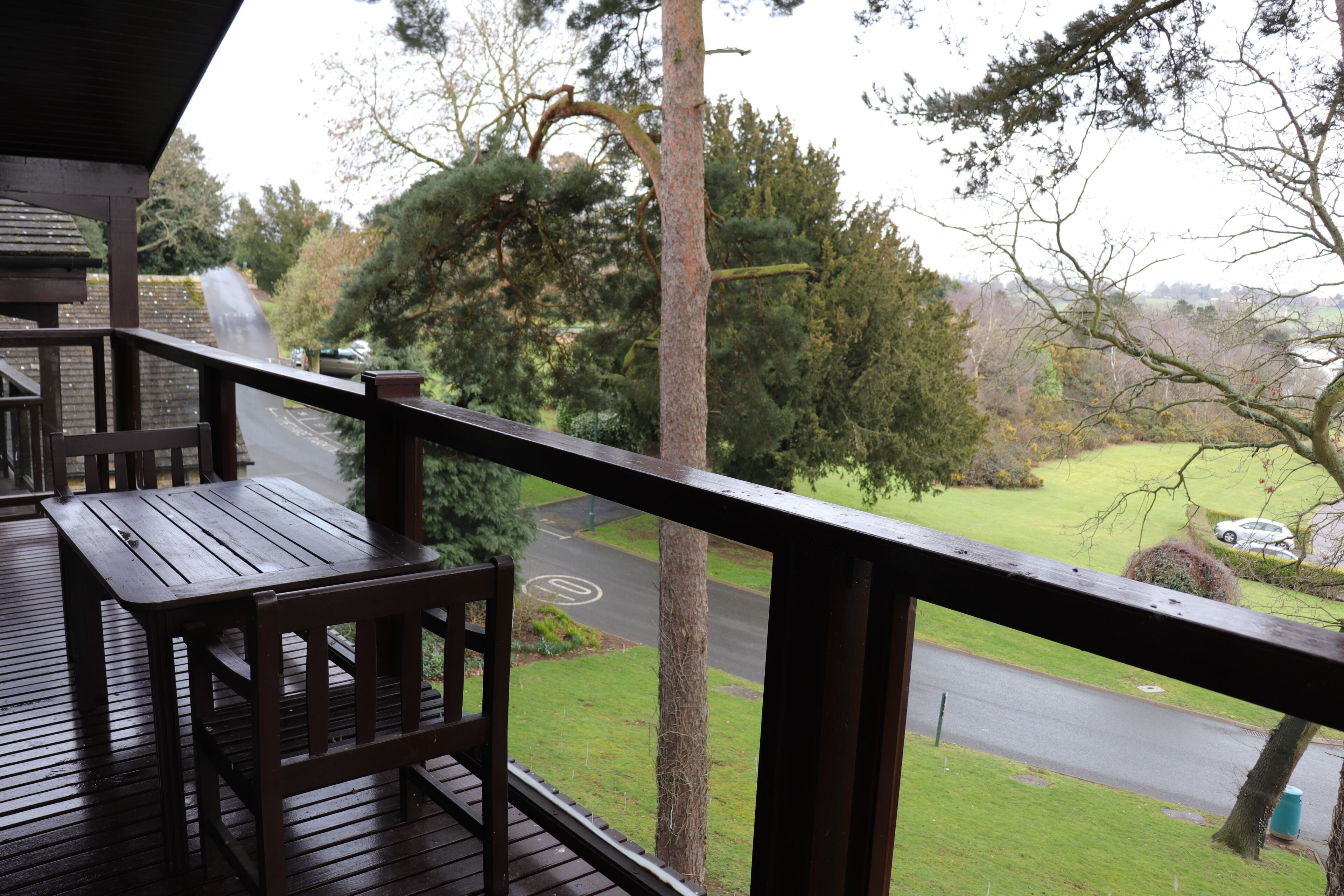 Une terrasse en bois offrant une vue sur une route et la végétation environnante.