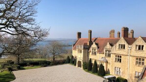 A large stone building with a gravel driveway and a vehicle parked in front. - Rutland Hall Hotel & Spa (Oakham)