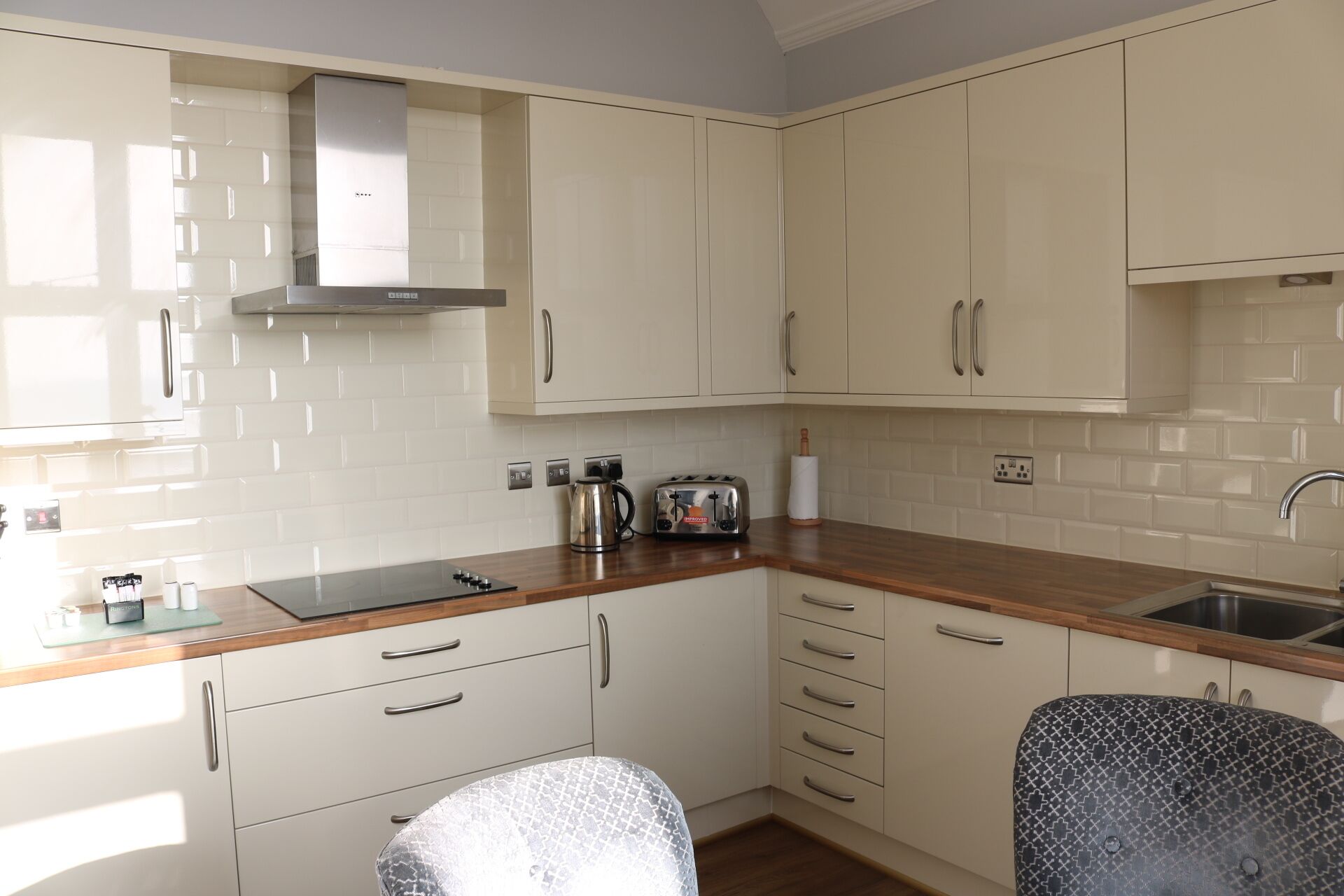 A compact kitchen with white cabinets, a wooden countertop, a built-in stove, and a sink.