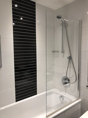 A modern bathroom with a glass-enclosed shower, a white bathtub, and black marble tiles. - Holiday Inn Northampton West M1, Jct 16 by IHG (Northampton)