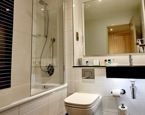 A modern bathroom with a glass-enclosed shower, a toilet, a sink with a mirror above, and toiletries on the countertop. - Holiday Inn Northampton West M1, Jct 16 by IHG (Northampton)