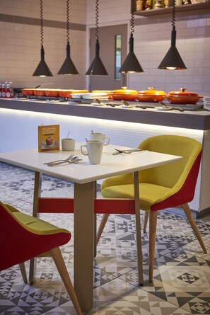 A dining area with a table, chairs, and a counter with kitchen utensils. - Holiday Inn Northampton West M1, Jct 16 by IHG (Northampton)