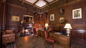 Una habitación formal con chimenea, muebles de madera y cuadros en las paredes.