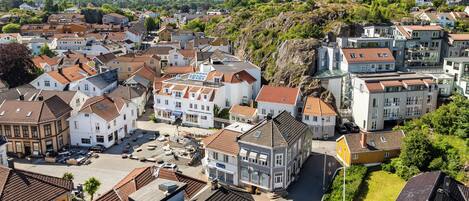 Ett bostadsområde med en blandning av moderna och traditionella hus, ett centralt torg med en fontän och en kuperad bakgrund.