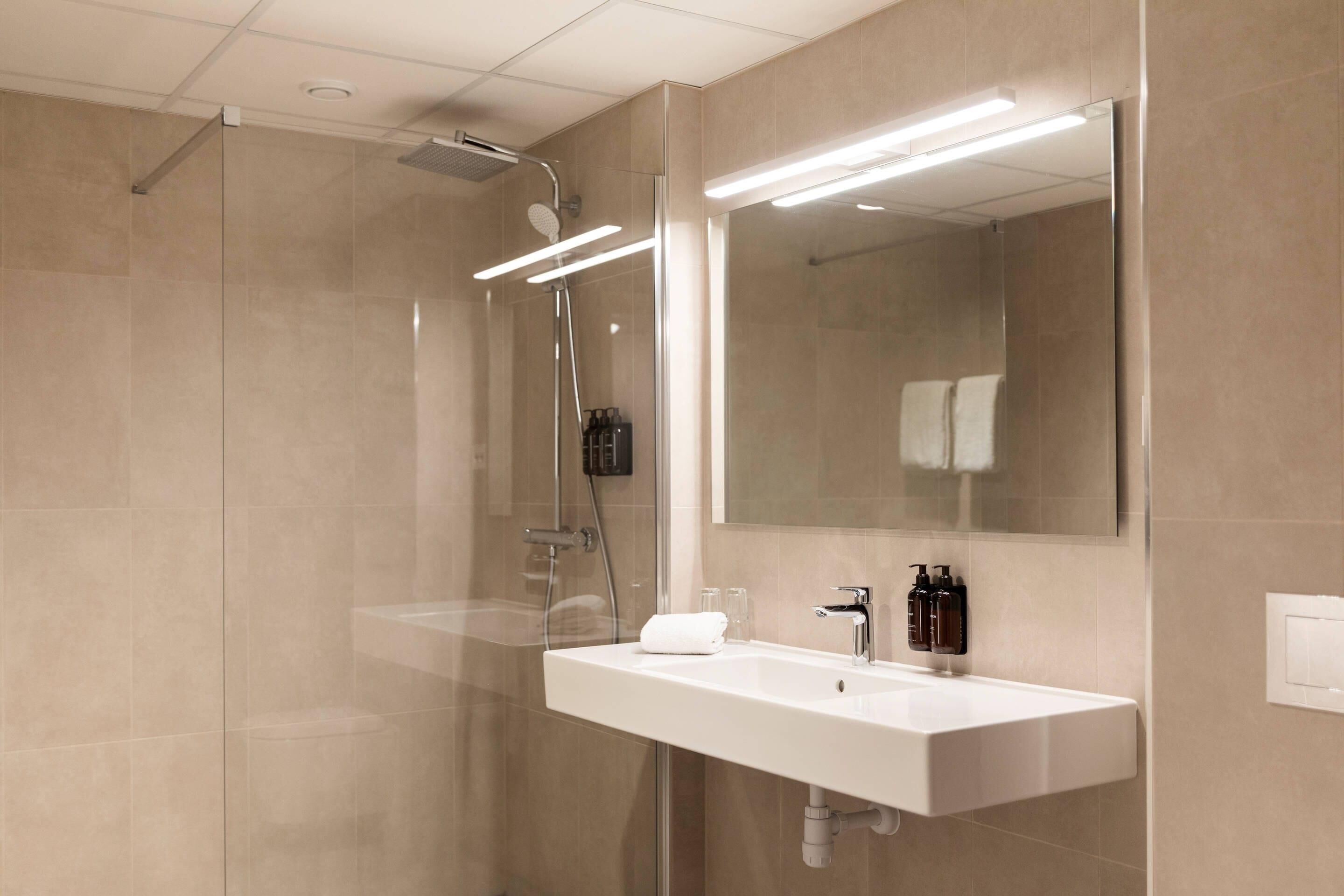 Un bagno moderno con doccia vetrata, lavandino bianco e uno specchio grande.