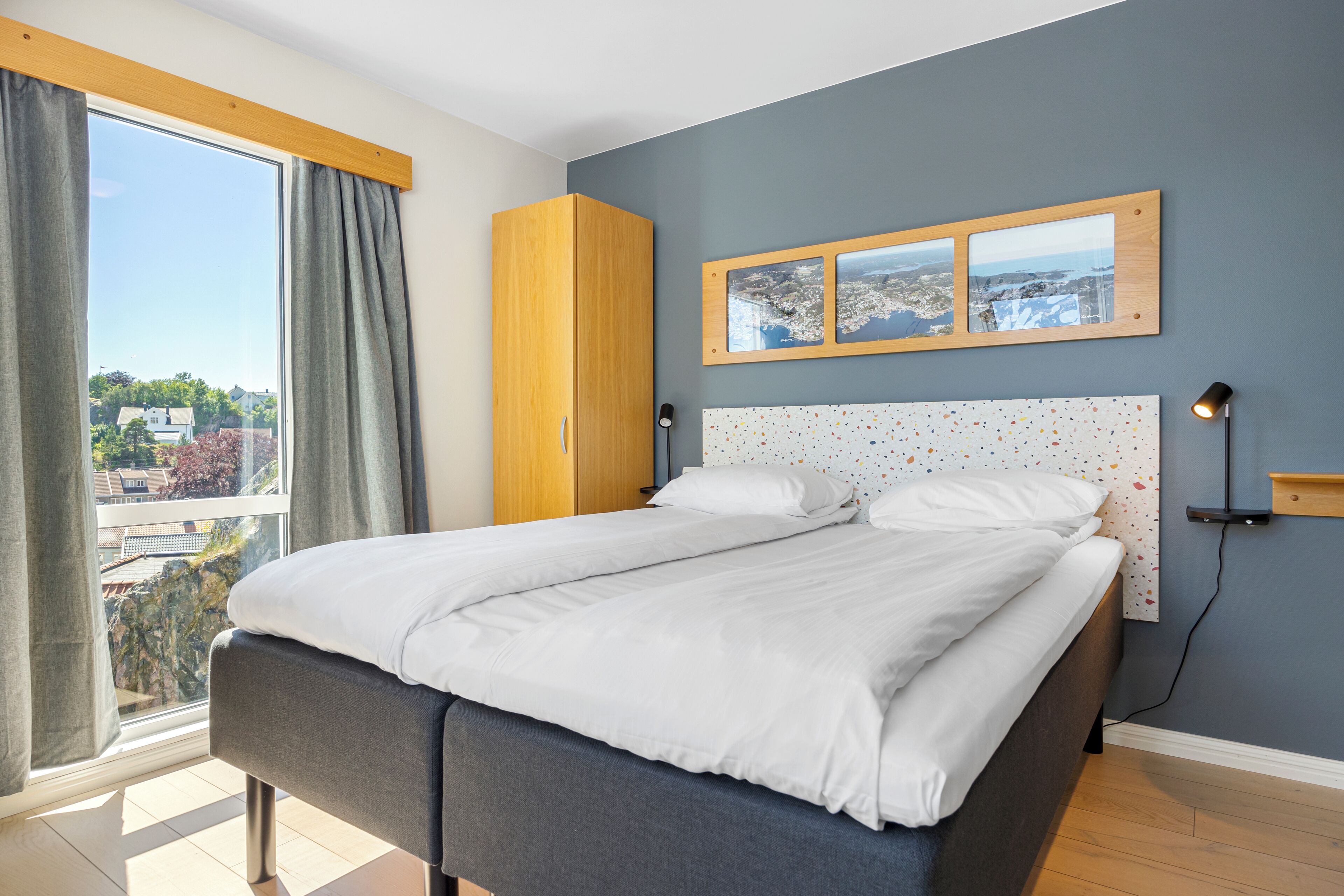 Un dormitorio con una cama grande, un armario, vistas a la ciudad y una lámpara de pared.