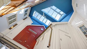 A high-ceilinged interior with skylights, a red door, and white walls. - Home Hotel Grimstad (Grimstad)