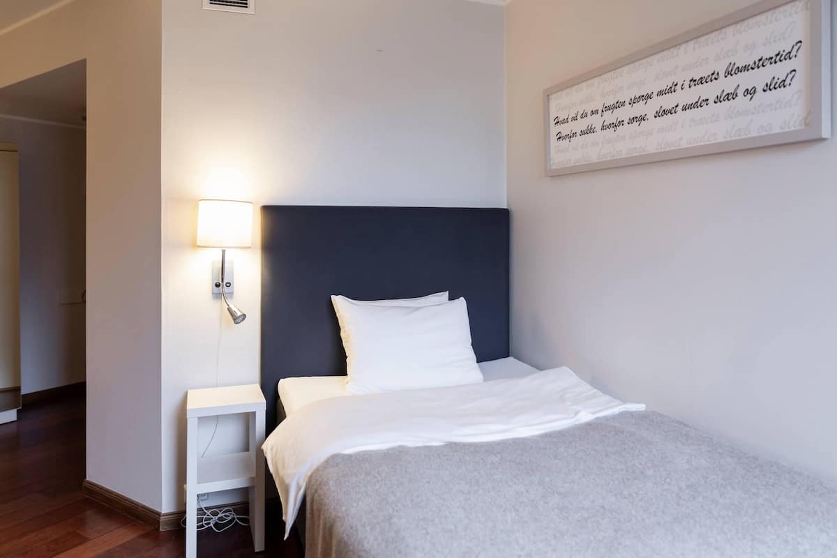 A neatly made bed with white linens in a hotel room.