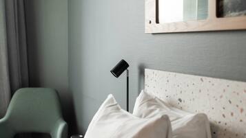 Ein Schlafzimmer mit einem grünen Sessel, einer Nachttischlampe und einem Bett mit gemustertem Kopfteil.