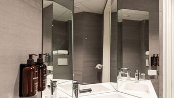 A modern bathroom with a large mirror, a white sink, and a shower area.