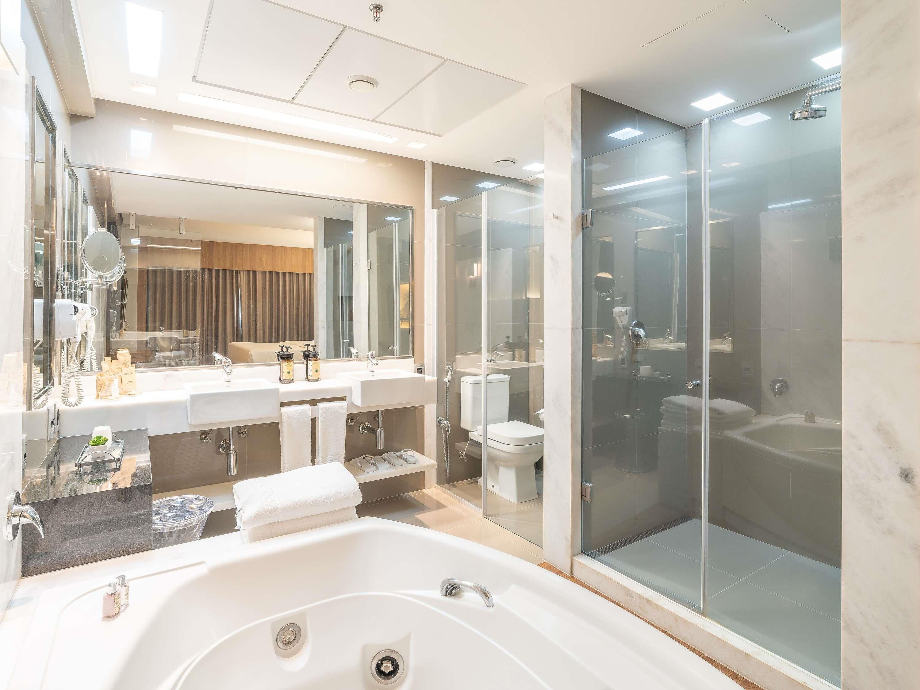 Un baño moderno con una bañera grande, dos lavamanos, una ducha con cerramiento de vidrio y un espejo sobre el lavamanos.
