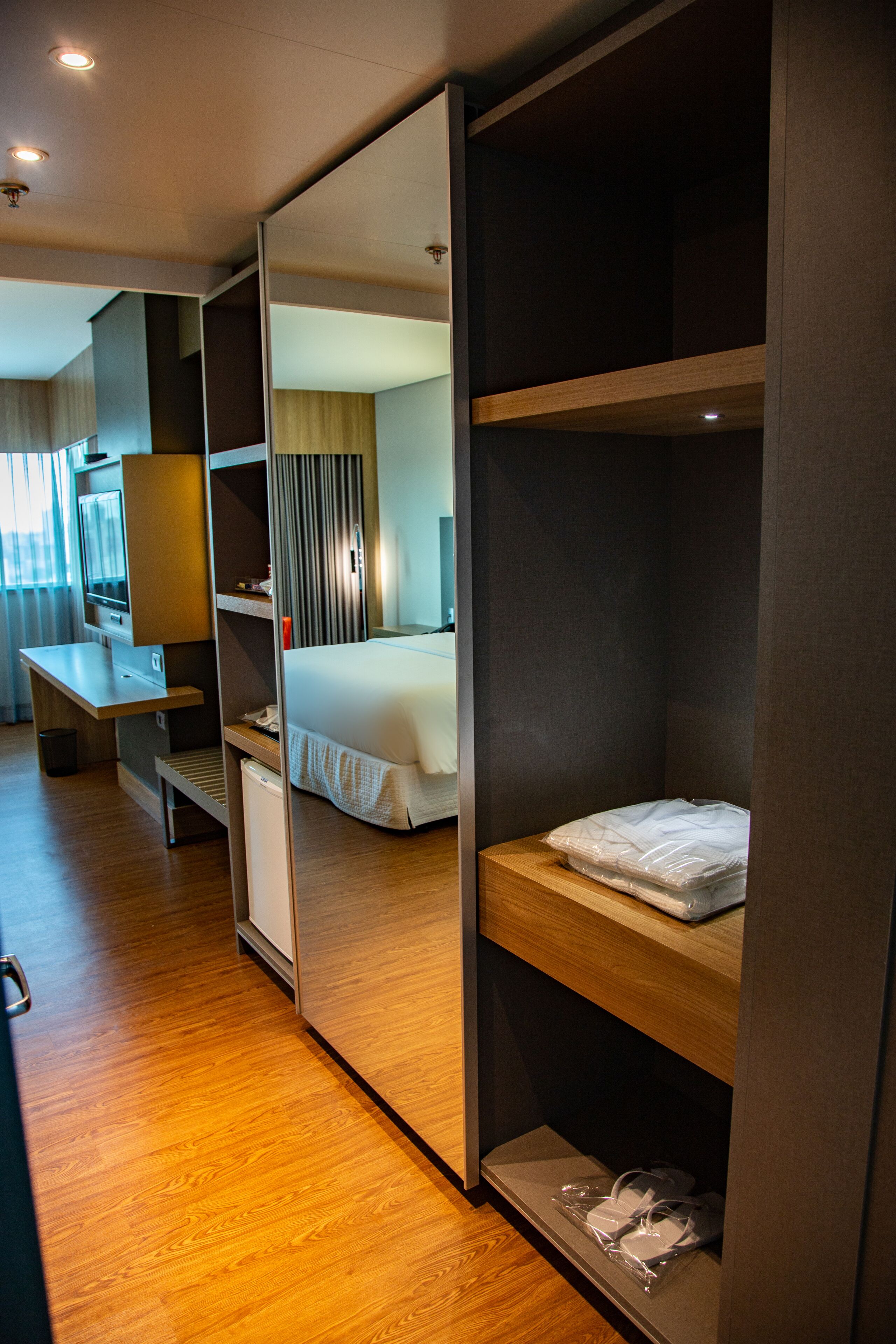 Ein Hotelzimmer mit Bett, Schreibtisch, Spiegel und Kleiderschrank.