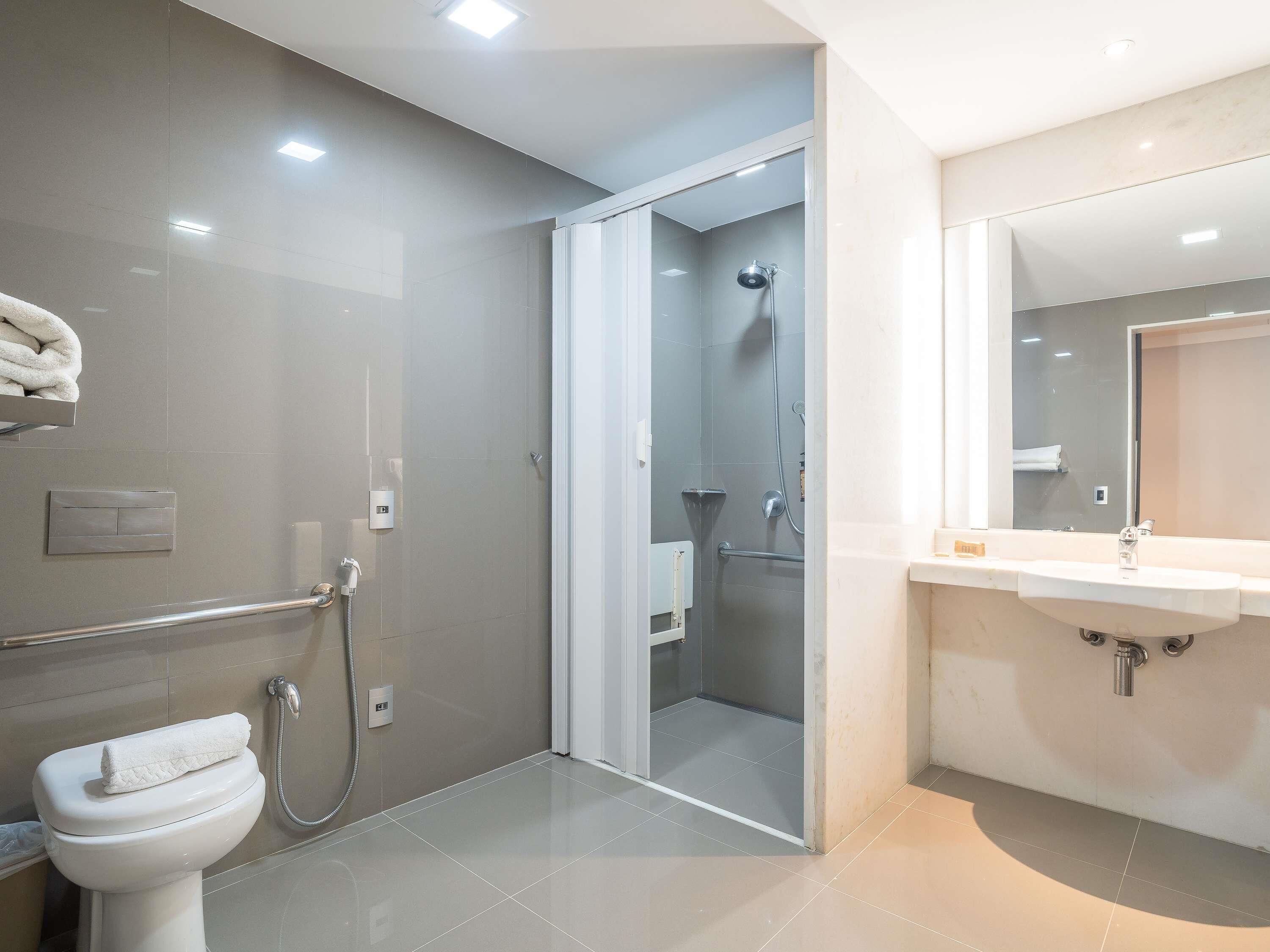 A modern bathroom with a toilet, shower, and sink.