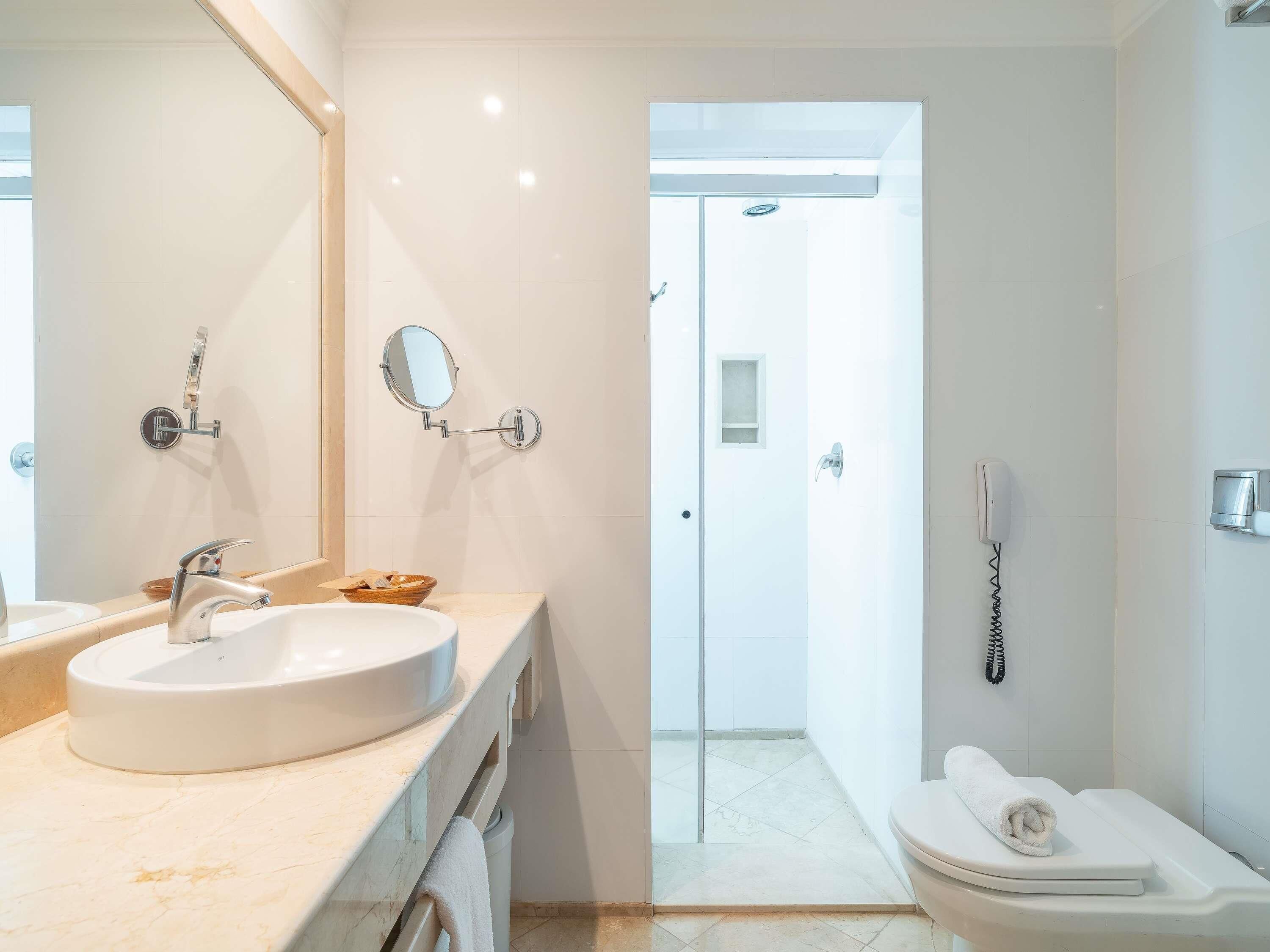 A modern bathroom with a sink, mirror, and toilet.