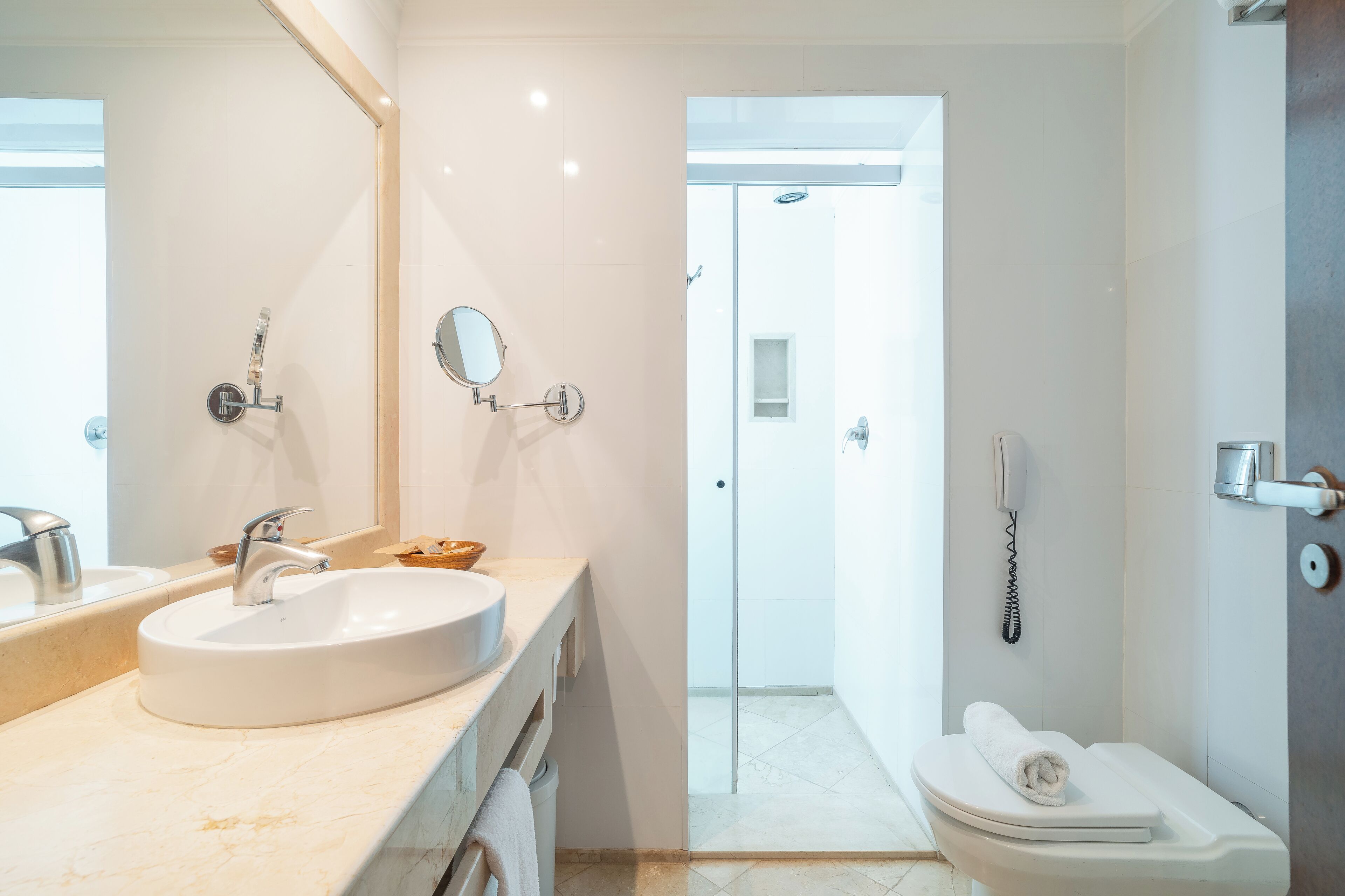 Ein modernes Badezimmer mit einem großen Waschbecken, einem Spiegel, einer Toilette und einer Duschkabine.