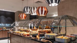 A buffet area with various food items and a glass display case. - Mercure Uberlândia Plaza Shopping (Uberlandia)