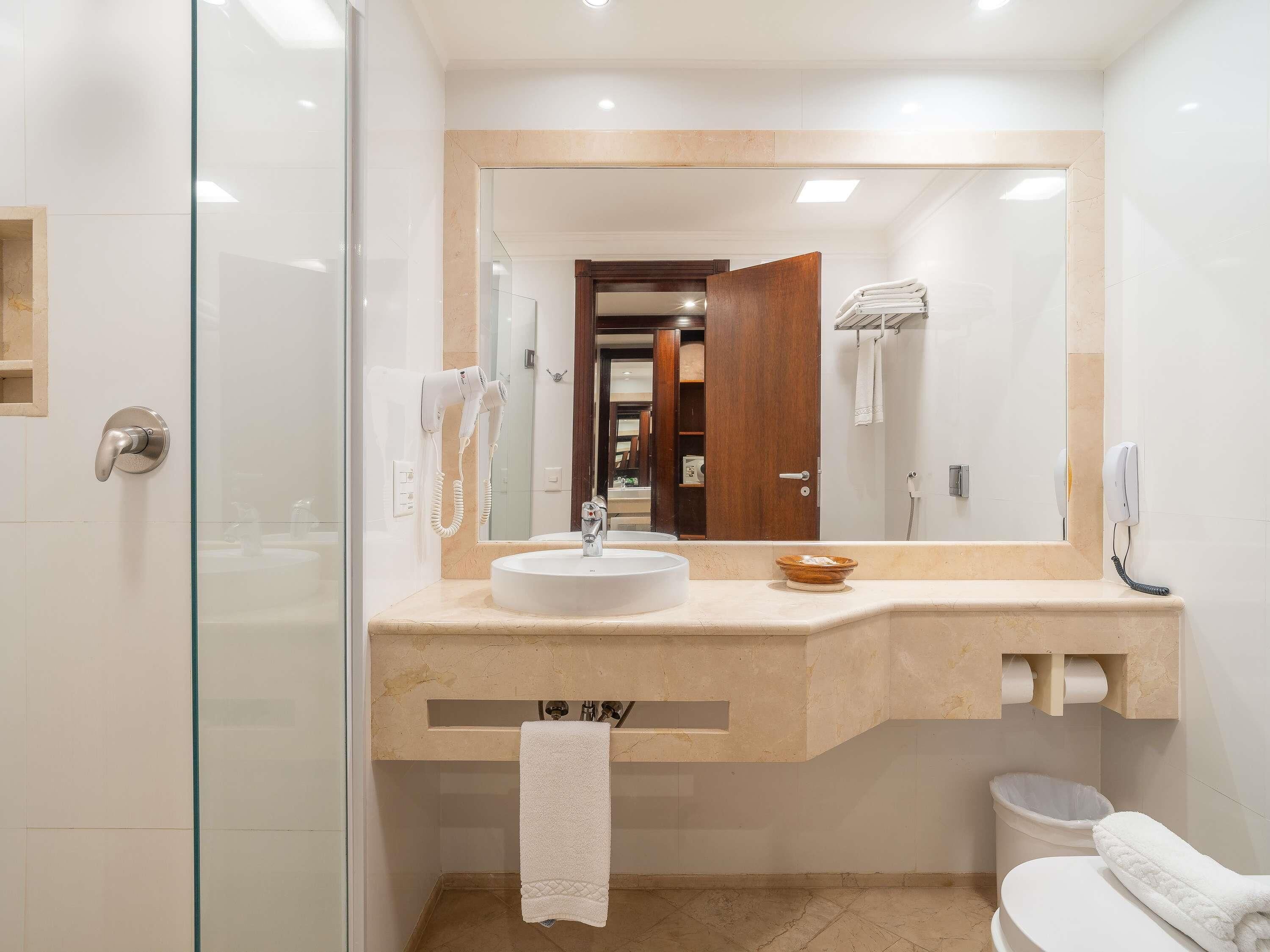 A modern bathroom with a glass shower enclosure, a sink with a towel, and a toilet.
