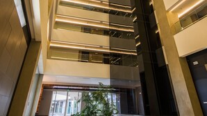 A modern interior with a central staircase, glass railings, and a reflective floor. - Mercure Uberlândia Plaza Shopping (Uberlandia)