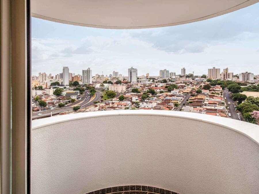 A cityscape view from a balcony with buildings, roads, and a clear sky.