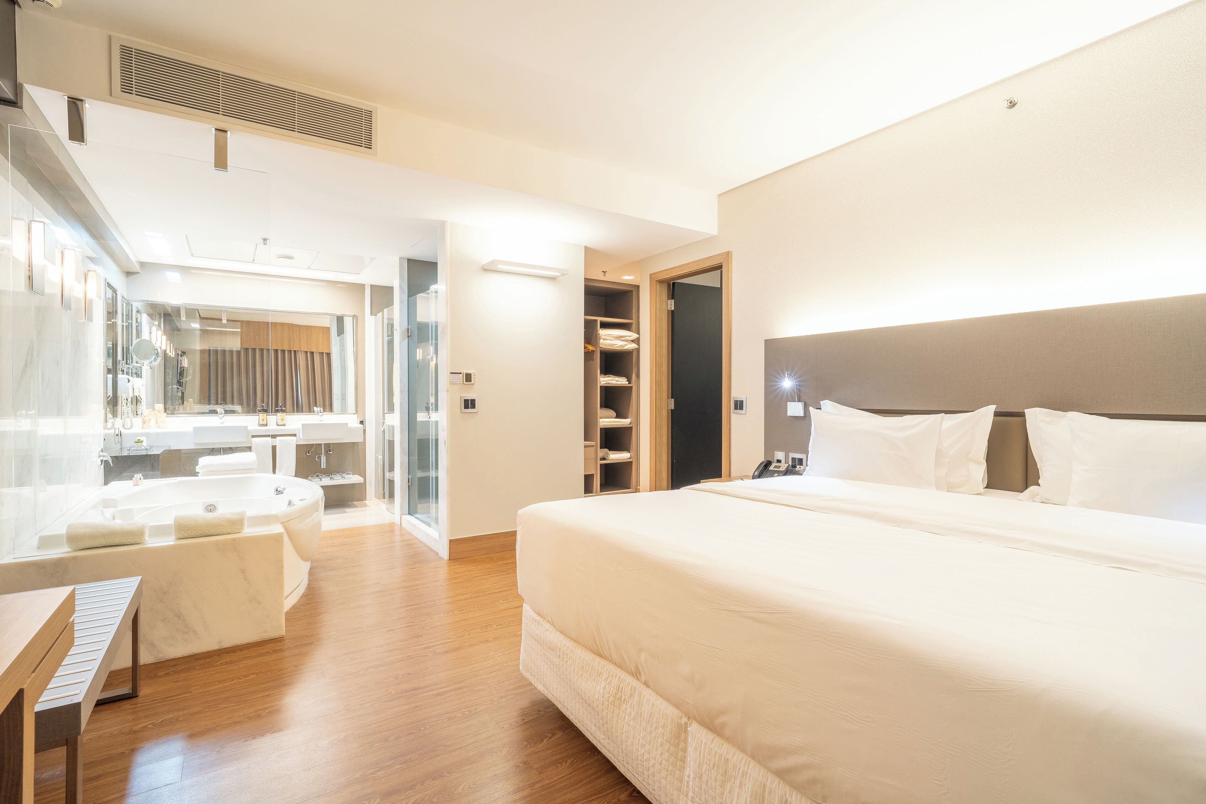 Ein modernes Hotelzimmer mit einem großen Bett, einem Schreibtisch und einem Badezimmer mit einer Badewanne.