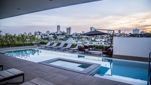 A rooftop pool with lounge chairs and a city view at sunset. - Mercure Uberlândia Plaza Shopping (Uberlandia)