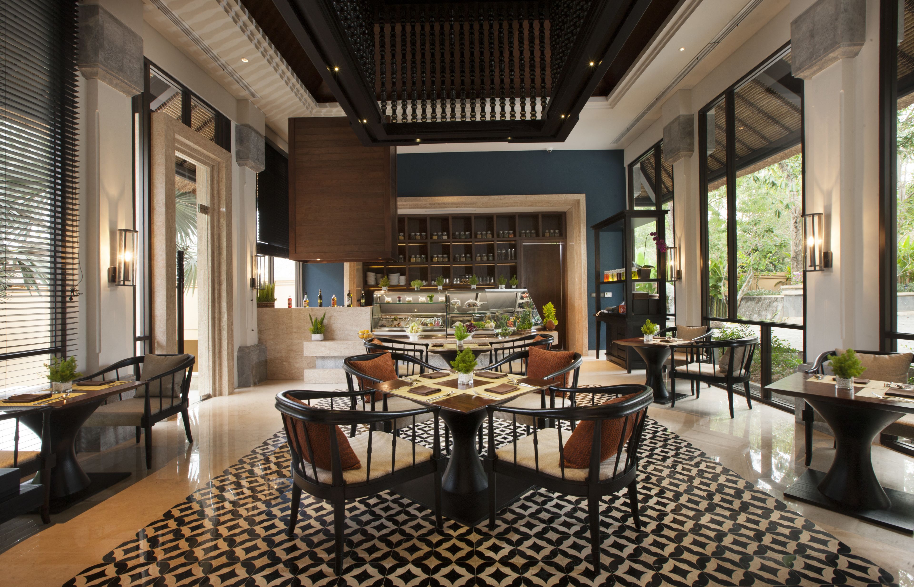A modern dining area with a central round table, surrounded by chairs, and a patterned floor.