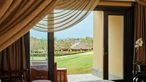 A room with a view of a well-manicured lawn, a traditional building, and a door leading outside.