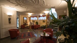 A lobby with red leather chairs, a red patterned rug, and a staircase leading to an upper floor. - Hotel Plaza Pescara (Pescara)