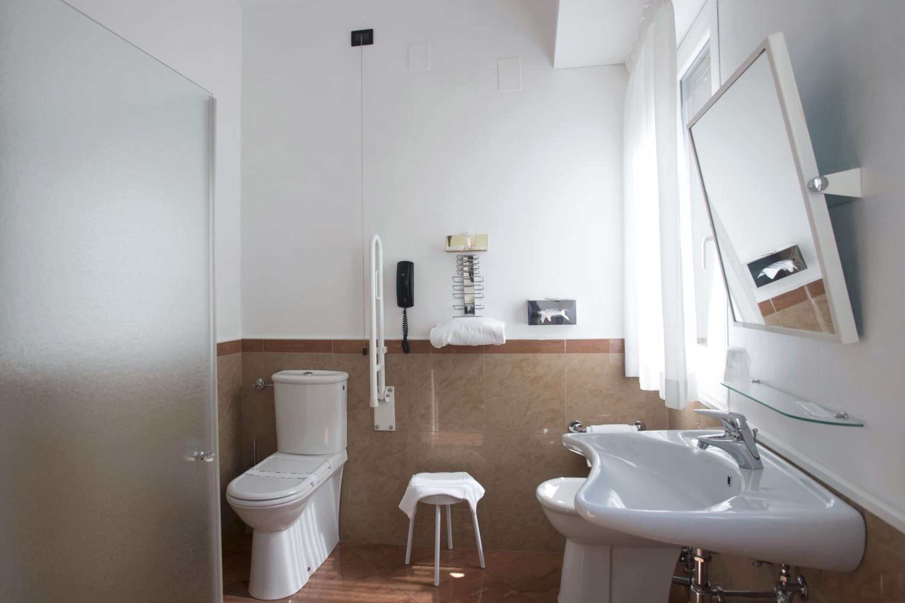 Et moderne badeværelse med toilet, bidet, vask og en brusekabine i glas.