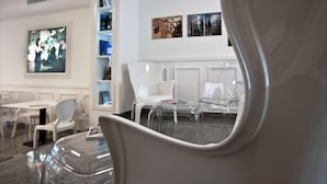 A modern interior with white furniture, a television, and framed artwork on the wall. - Hotel Plaza Pescara (Pescara)
