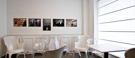 Un interior moderno con sillas transparentes, una mesa y obras de arte en la pared.