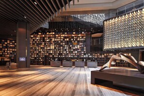 Interior de una biblioteca moderna con un mostrador de recepción central, estanterías y una escultura metálica única.