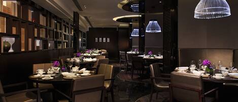 A restaurant with multiple tables, chairs, and a modern chandelier.