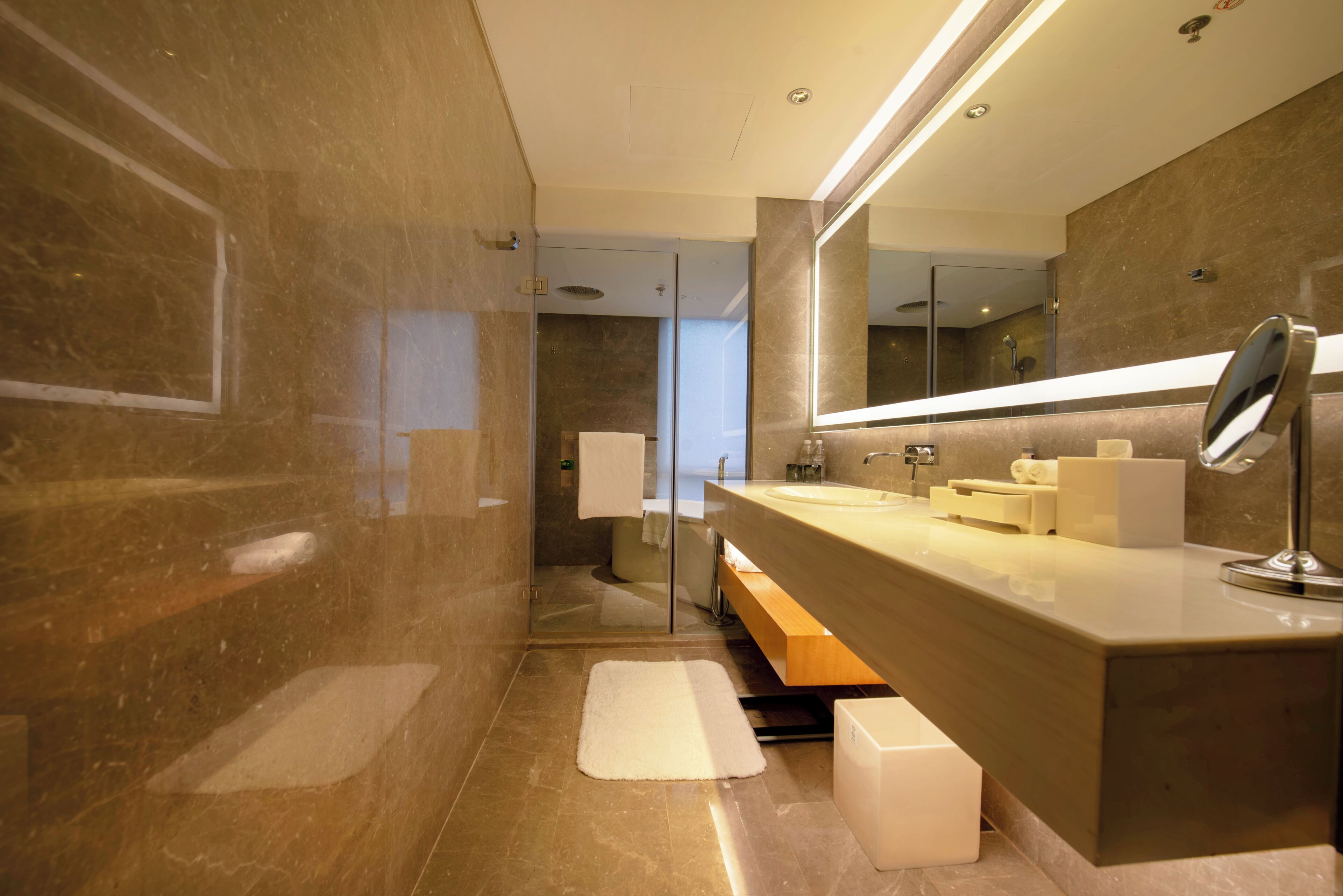 Un baño moderno con un espejo grande, un lavamanos y una zona de ducha.
