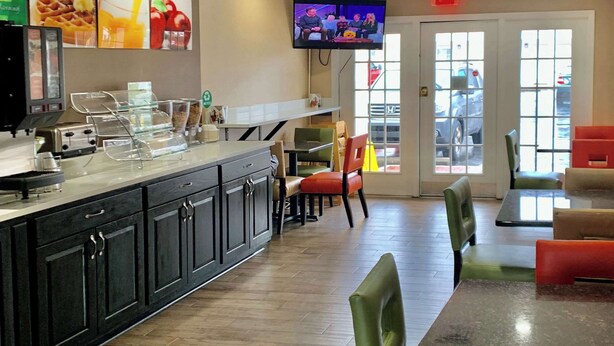 A restaurant interior with a counter, seating area, and a TV mounted on the wall.