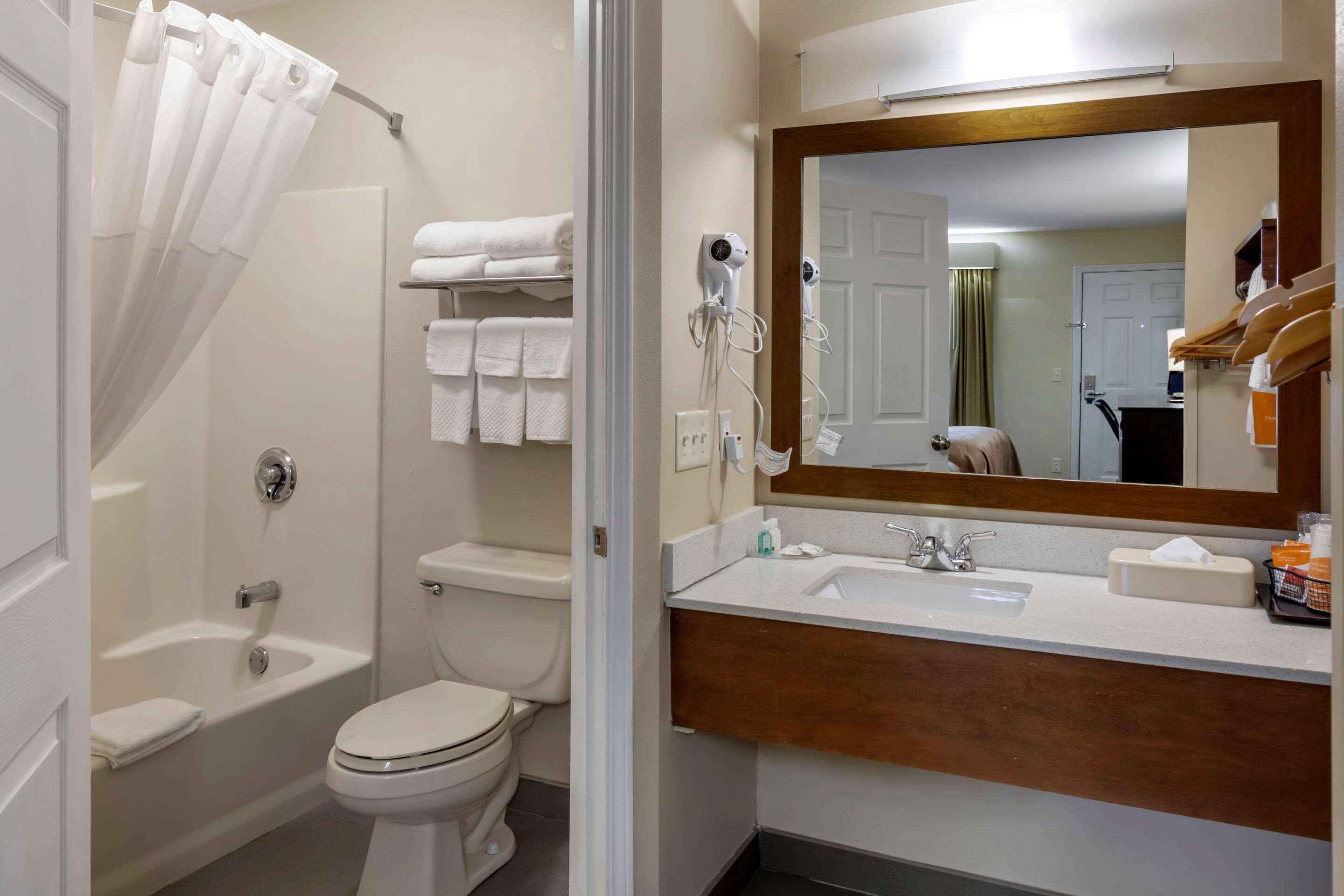 Un baño con bañera, inodoro y tocador con espejo.