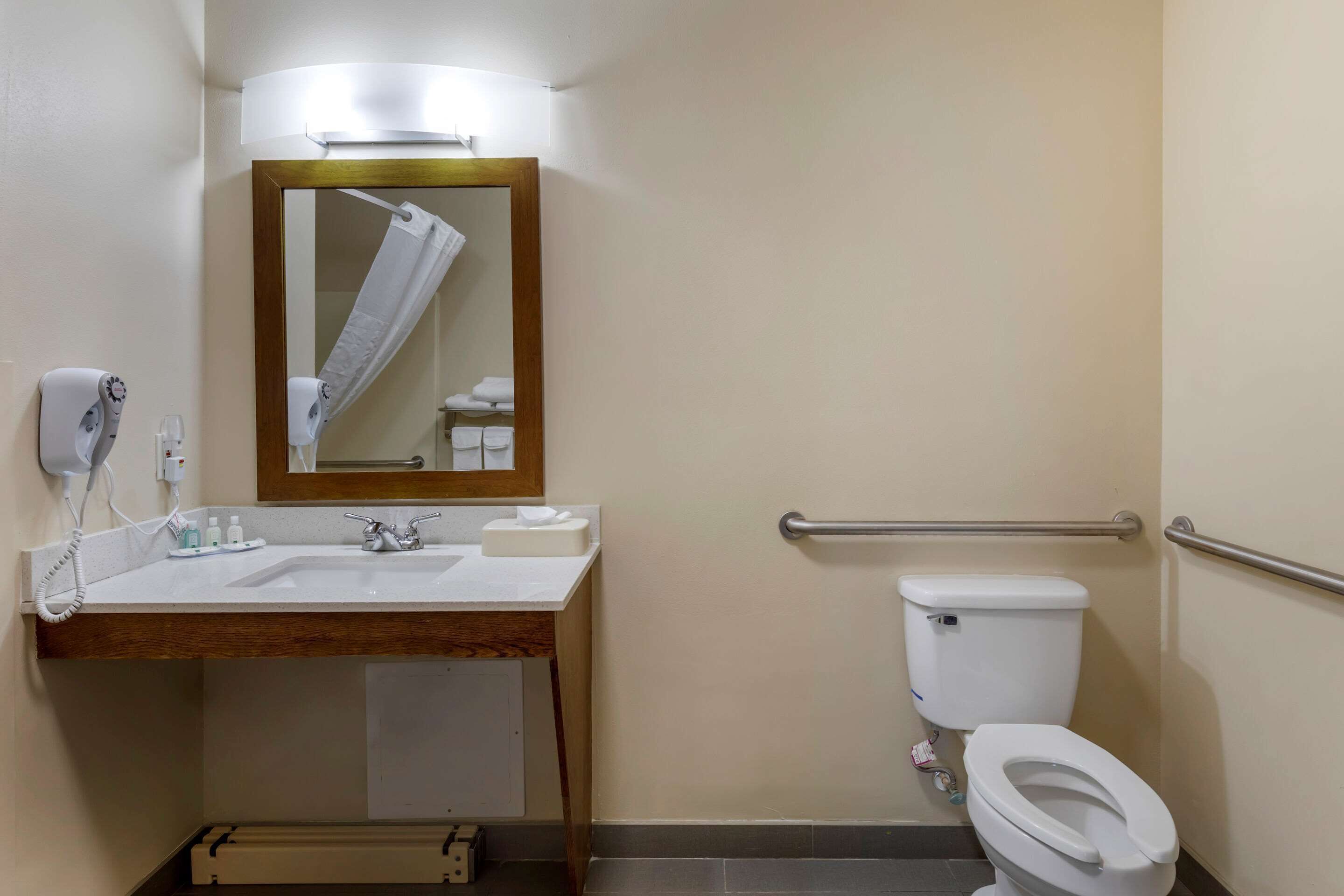 Ein Badezimmer mit Waschbecken, Spiegel, Handtuchhalter, Toilette und Handtrockner.