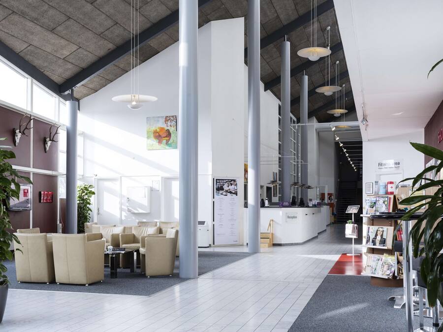 A spacious lobby with high ceilings, large windows, and a reception desk.