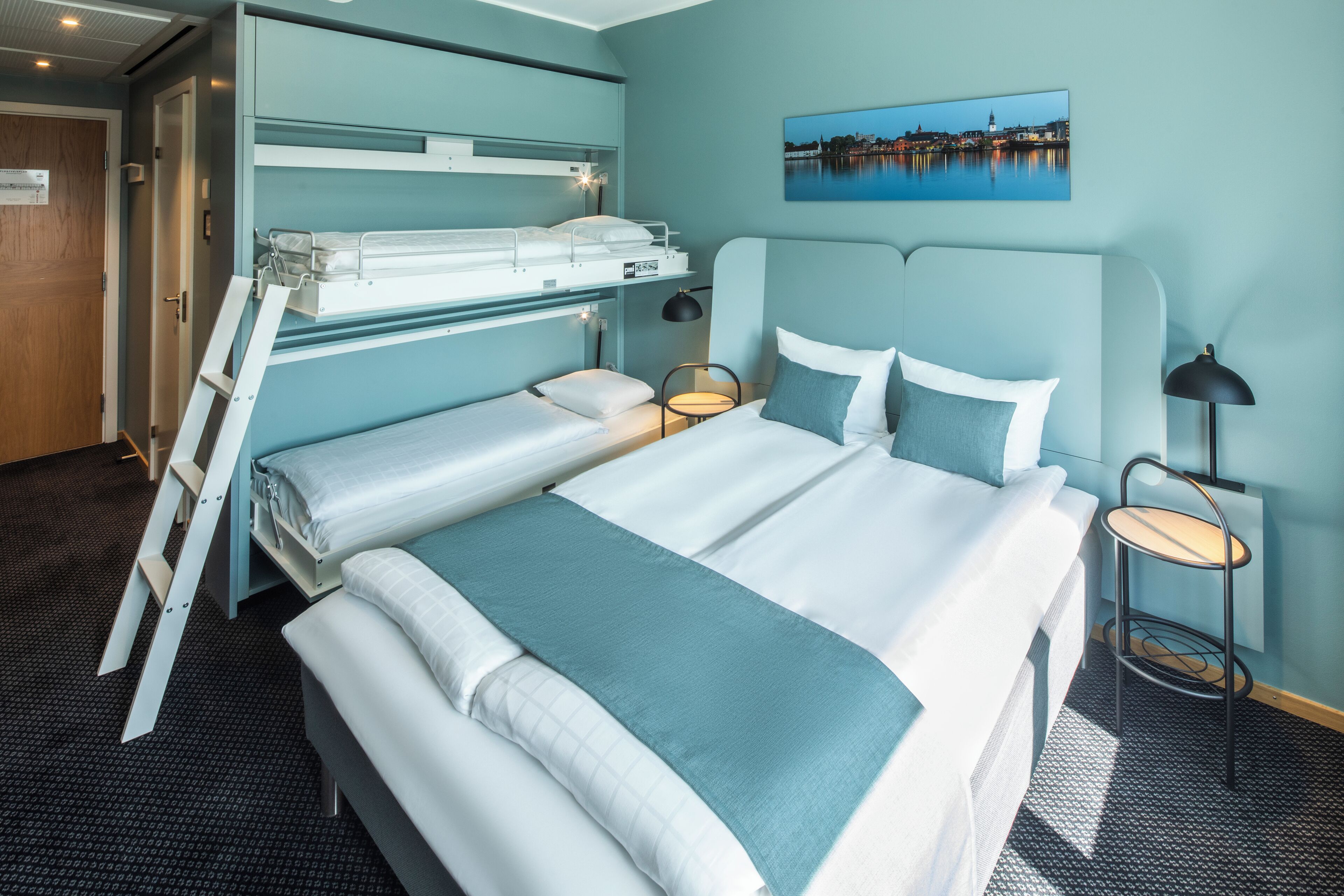 Une chambre d’hôtel avec des lits superposés, un bureau et une table de chevet.